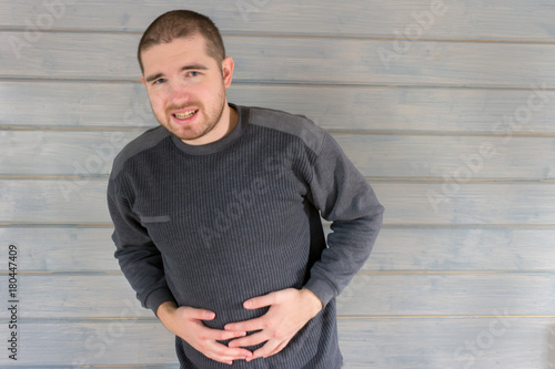 a man in a gray sweater hurts his stomach photo