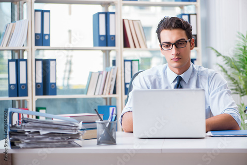 Businessman with excessive work paperwork working in office