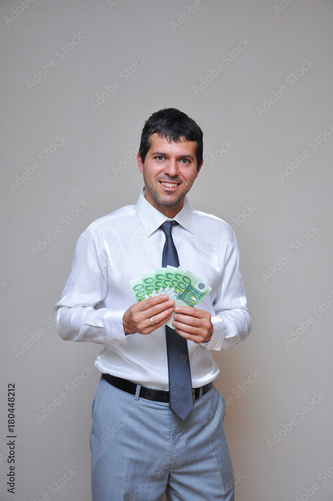 Happy and successful businessman holding pile of money. Young man with pile of euro banknotes Happy and successful businessman holding pile of money. Young man with pile of euro banknotes