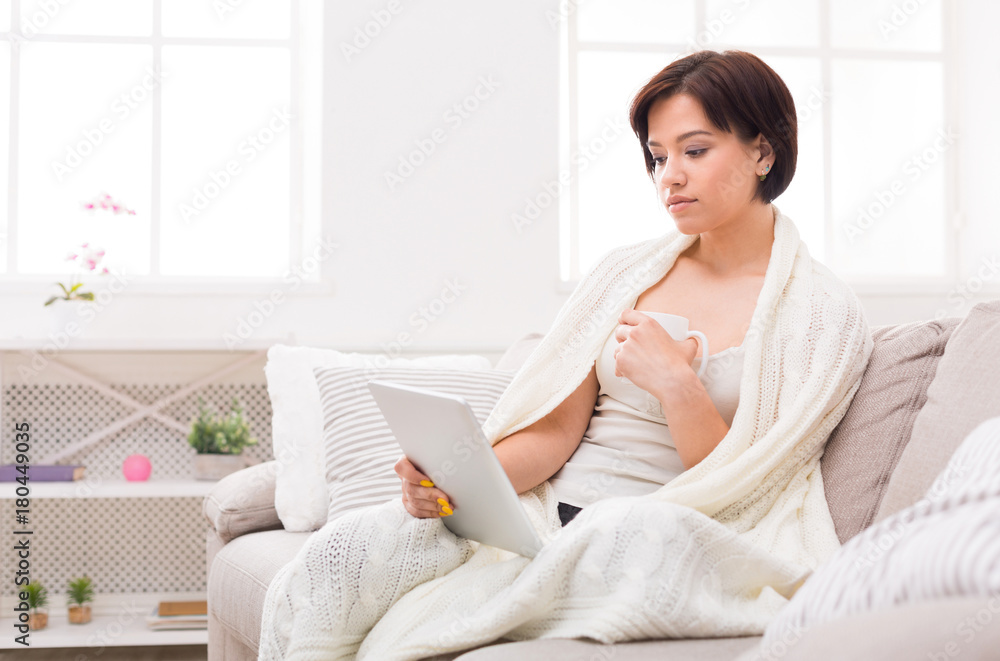Home comfort. Thoughtful girl in a blanket with a tablet Home comfort. Thoughtful girl in a blanket with a tablet