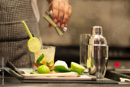 A professional bartender is making cocktails for customers. Meticulously