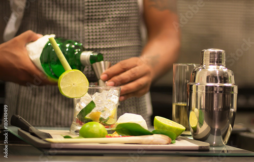 A professional bartender is making cocktails for customers. Meticulously