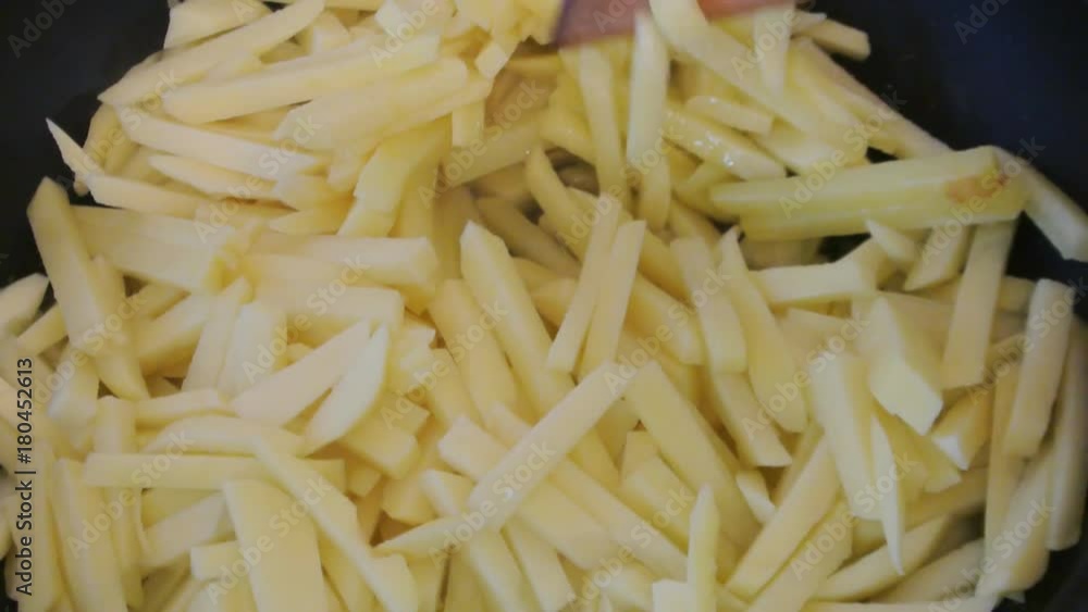 Female hands turn fries with a wooden spatula. Home kitchen. Female hands turn fries with a wooden spatula. Home kitchen.