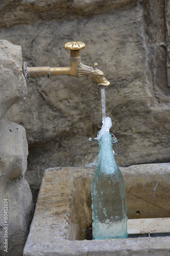 Auffüllen einer Wasserflasche am Brunnen
