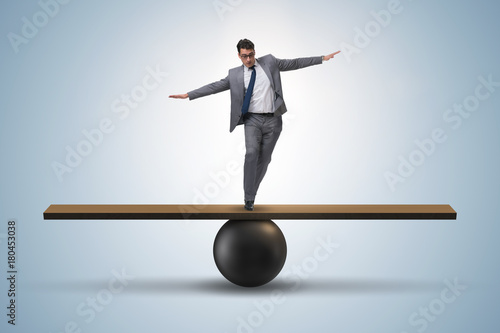 Fotografie, Tablou Businessman trying to balance on ball and seesaw