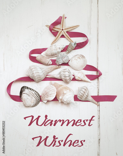 Christmas tree shape made out of saltwater shells with a starfish on top on a natural, textured background. Great image for Christmas in warm climates or Southern Hemisphere. Message added