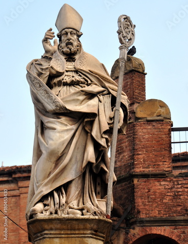 Statue des Bischofs St. Petronius mit erhobener Hand und Stab vor einem backsteinernen Stufengiebel photo