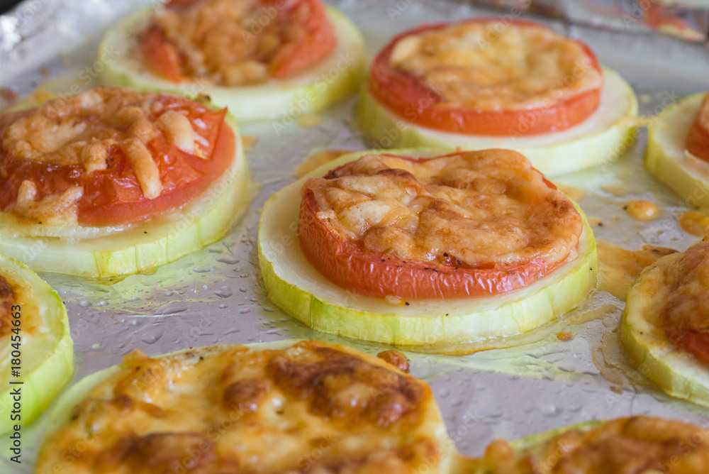 Slices of tomato and zucchini under cheese crust Slices of tomato and zucchini under cheese crust