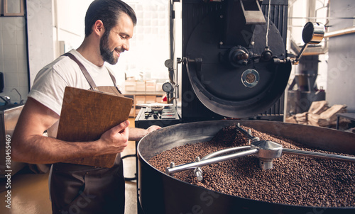 Foto Side view cheerful bearded worker checking grains situating in special equipment