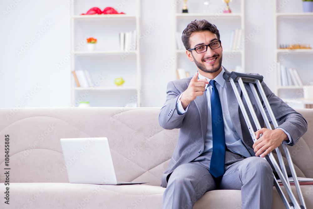 Businessman with crutches and broken leg at home working Businessman with crutches and broken leg at home working