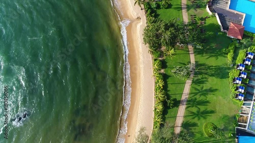 Aerial view from the top of hotel and sandy beach that washing by sea waves in Sri Lanka