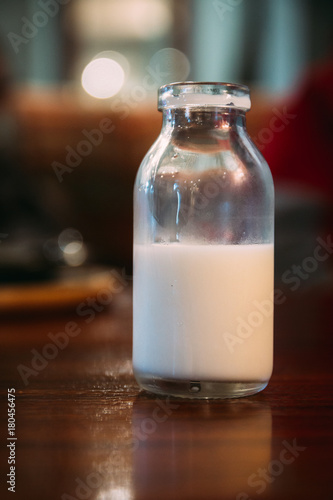 old style milk cream bottle on a table, portrait orientation, half empty