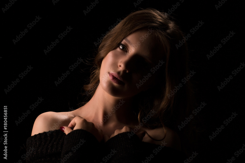 Woman lighted half face, portrait of young light hair model woman posing on black background in studio Woman lighted half face, portrait of young light hair model woman posing on black background in studio