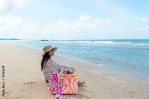 Freedom lifestyle asian woman sitting on the beach looking at the sea and sky.  Travel and Summer Concept.