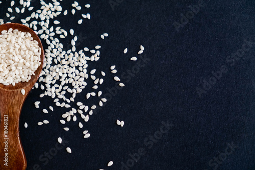 Organic natural sesame seeds wooden spoon. toasted sesame seeds. Raw, whole, unprocessed. Natural light. Selective focus. Close up on a black background. Top view, flat lay. copy space for text. photo