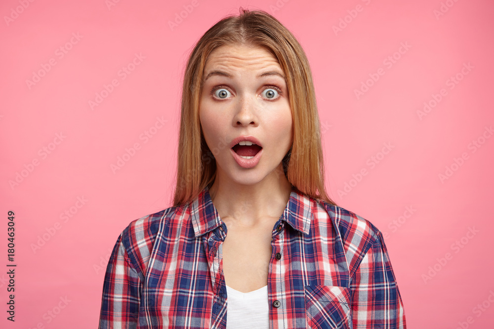 Terrified horrified puzzled female with bugged eyes and jaw dropped out being shocked to find out about dismissal from office or discharge, poses in pink studio. Hearing unexpected bad news. Terrified horrified puzzled female with bugged eyes and jaw dropped out being shocked to find out about dismissal from office or discharge, poses in pink studio. Hearing unexpected bad news.