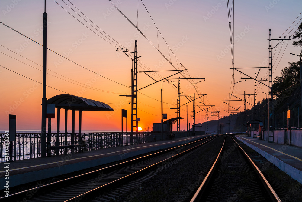 The platform of the railway station and the railroad going into the distance at sunset, Sochi, Russia
