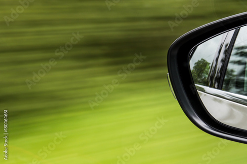 Car wing mirror abstract zooming past grass road