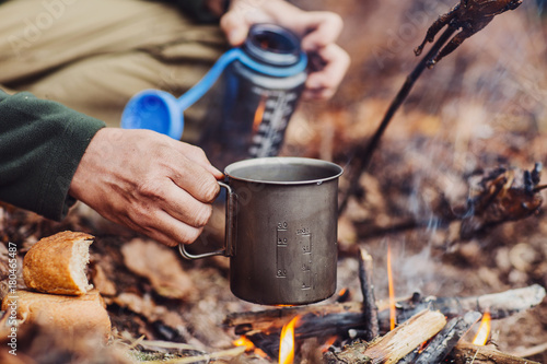 hunter pours water from a bottle into a metal mug.