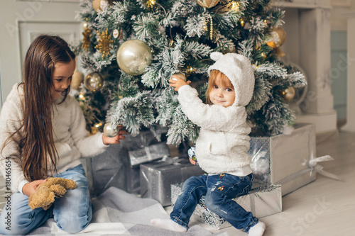 Two girls with santa hat laying in front of the christmas tree photo