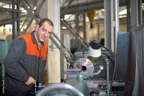 metalworking industry  factory man worker in uniform working on lathe machine in workshop