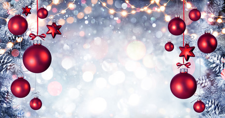 Red Christmas Balls Hanging With Snowy Fir branches And String Lights