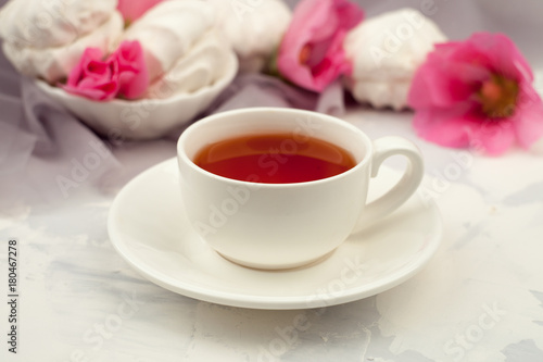 cup of tea, sweets and a pink flowers on a light background