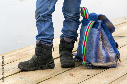 Kid boy legs and backpack on a wooden pier
