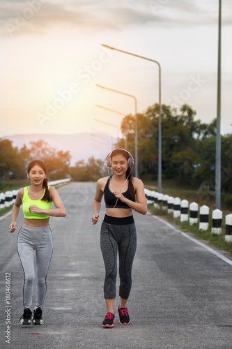 Happy and beautiful women joggers running on road. Fitness and workout wellness concept.