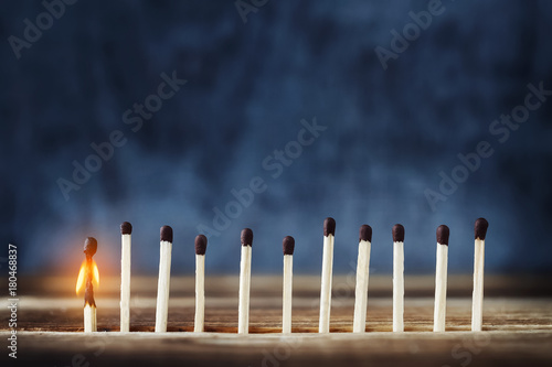 row of matches, one match burns and fades