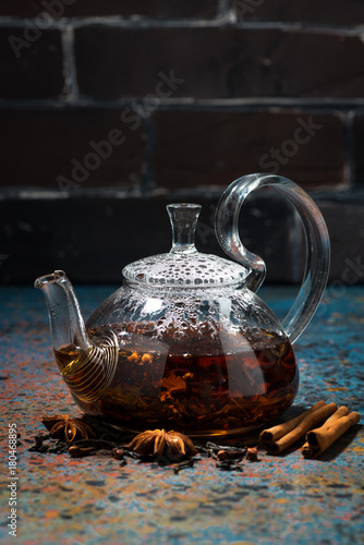 tea masala in a glass teapot on a dark background, vertical