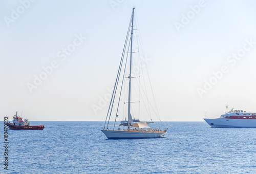 One fancy boat docked at sea and three boat passing by with clean blue sky