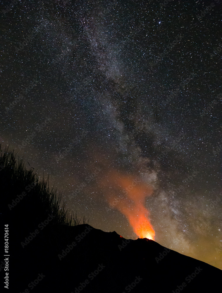 Erupting volcano Stromboli, Italy, at night with prominent Milky Way.