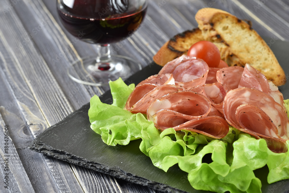 cold meat plate. Sliced ham with lettuce leaves on a dark stone background, selective focus