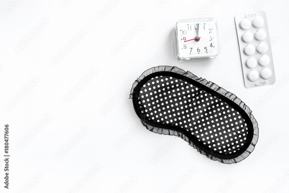 Sleeping pills for insomnia near sleep mask and alarm clock on white background top view copyspace Sleeping pills for insomnia near sleep mask and alarm clock on white background top view copyspace