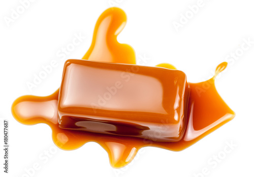 Caramel sauce flowing on caramel candies, isolated on white background. Golden Butterscotch toffee candy caramels.