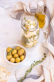 Green olives, feta cheese with olive oil in a jar and fresh ciabatta