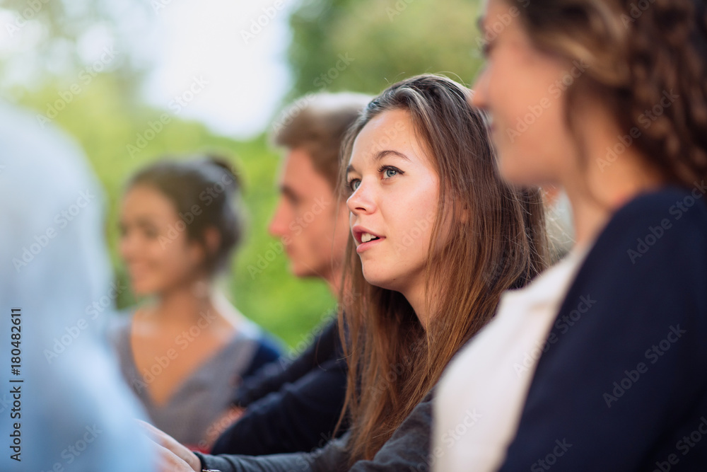 Group of young people having fun outside, focus on a young woman Group of young people having fun outside, focus on a young woman