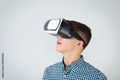 Young boy in virtual reality goggles on grey background © 5second