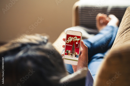Woman holding mobile phone and using an Christmas shopping app to buy gifts.