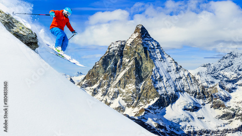 Man jumping from the rock, skiing on fresh powder snow with Matterhorn in background, Zermatt in Swiss Alps.
