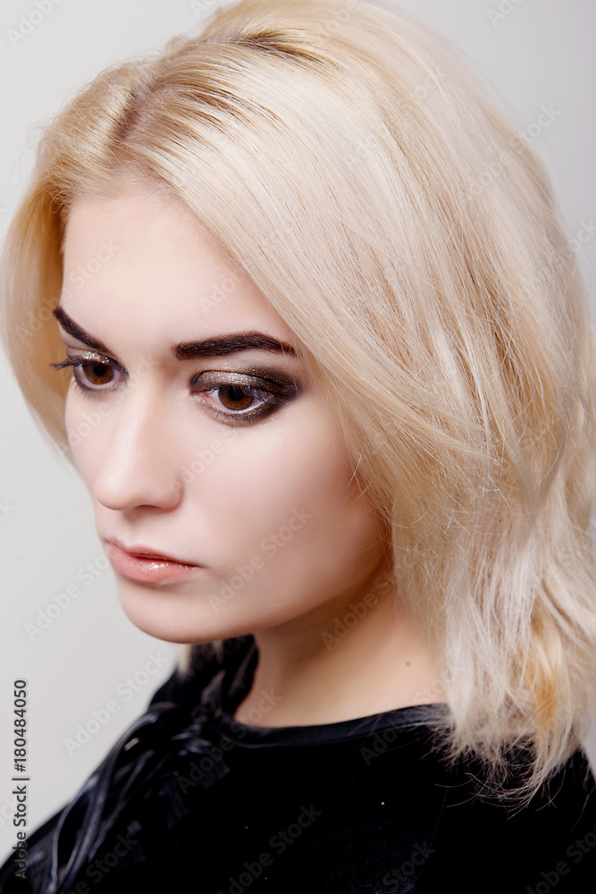 Blonde girl with bright makeup looking down on the white isolate close-up Blonde girl with bright makeup looking down on the white isolate close-up