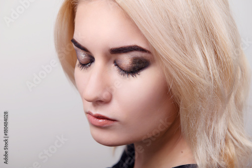Blonde girl with bright makeup on the eyes closed and clean skin on a white isolate close-up