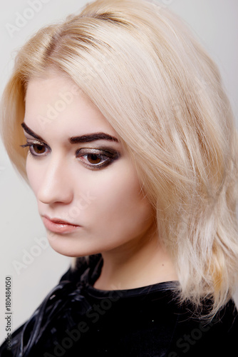 Blonde girl with bright makeup looking down on the white isolate close-up