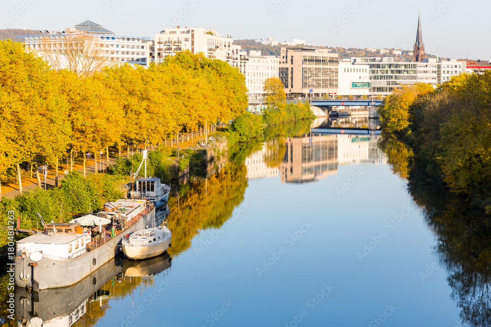 boats on river near promenade leading to city center with shopping malls and church