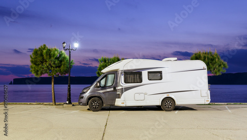 Motorhome RV and campervan are parked on a beach. Motor home caravans are parked on a parking space for RV vehicles by Aegean sea in Greece. Night scenery.