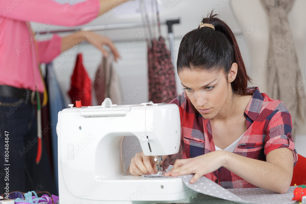 young woman is sewing cloth with sewing machine