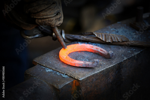 Photo The blacksmith kicks a horseshoe