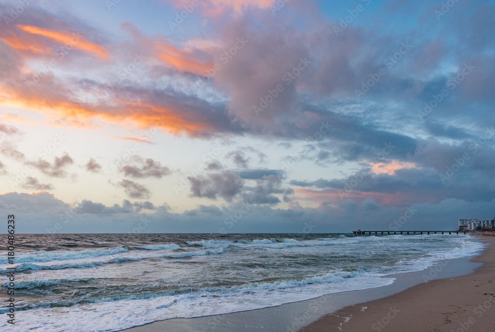 mostly cloudy skies over the ocean and pier at sunrise