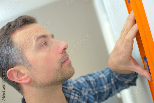 man using spirit level on white wall at home